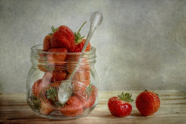 Frasco de vidrio con cuchara junto con fresas