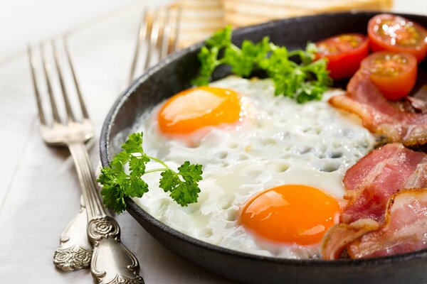 Ein köstliches Frühstück mit zwei Eiern und Speck mit Tomaten