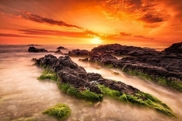 Puesta de sol roja sobre las piedras del mar