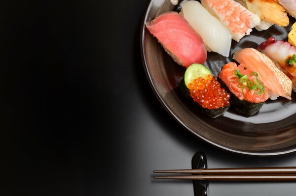 Sushi mit Stäbchen auf schwarzem Hintergrund