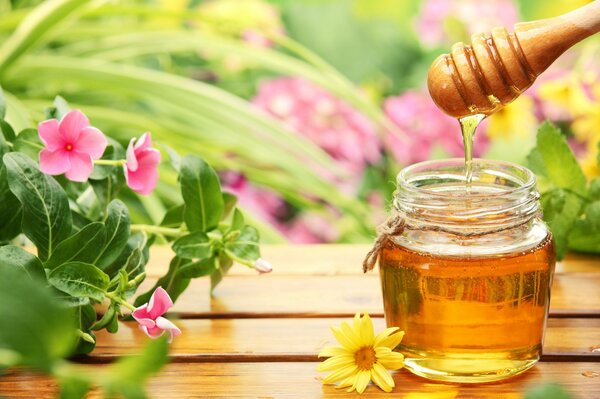 Miel sobre la mesa en un fondo de flores