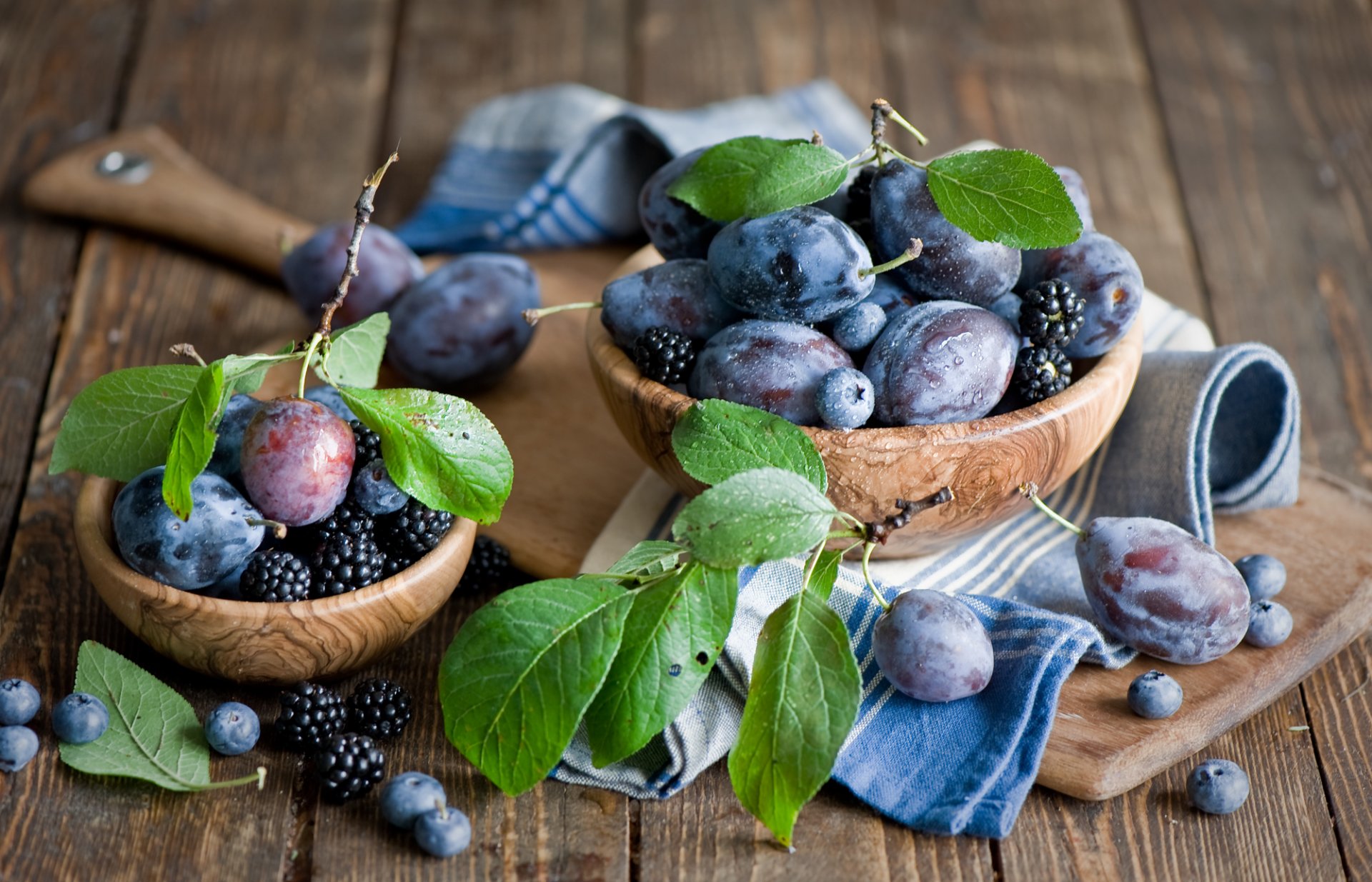 pflaumen brombeeren blaubeeren beeren früchte blätter tafel geschirr aus holz stillleben anna verdina