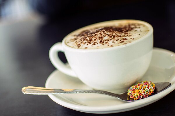 Cappuccino con espuma y cuchara en platillo