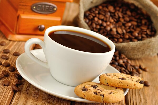 A cup of coffee with cookies and coffee beans