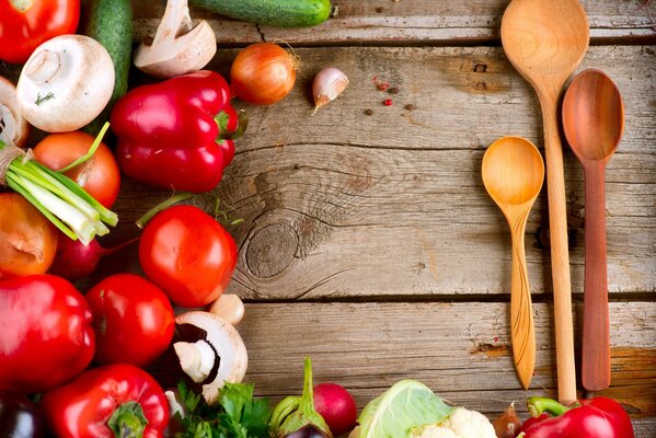 Wooden spoons and vegetables on a wooden table