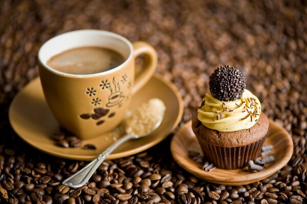 Against the background of coffee beans there is a mug of coffee and a cake