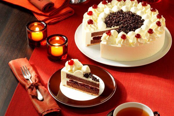 Tea with a cake on a red tablecloth by candlelight