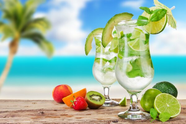 Zwei Mojito-Cocktails mit Sonnenschirmen und Beeren und Früchten