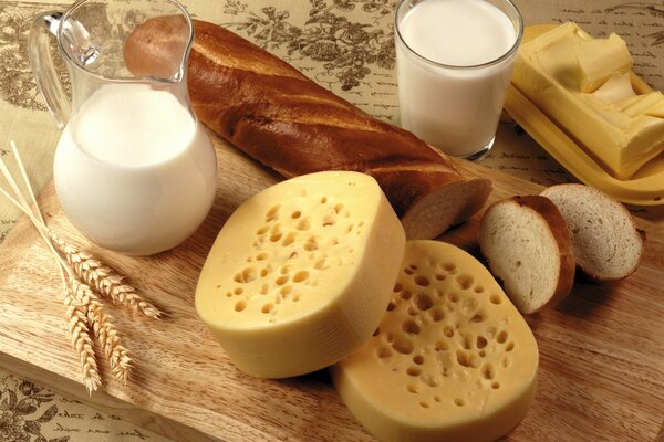 Bodegón comestible de leche, pan, queso y mantequilla adornado con cereales en una tabla de madera