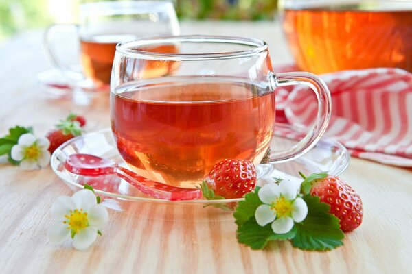 Eine Tasse Tee auf einem Tisch mit Erdbeeren im Hintergrund