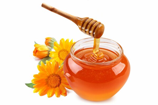 A jar of transparent honey and orange flowers