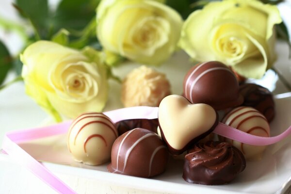 Sweets made of milk and white chocolate in a plate on a background of roses