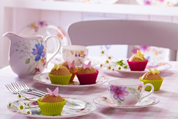 Muffins decorados con mariposas y tazas de porcelana