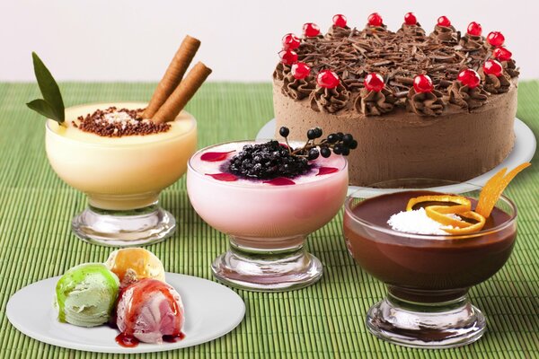 Three cream desserts, ice cream balls on a plate and a chocolate cake decorated with berries on a platter