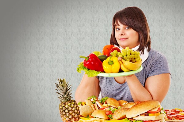 Jeune fille tenant un plateau de fruits. Burgers et sandwiches sur la table