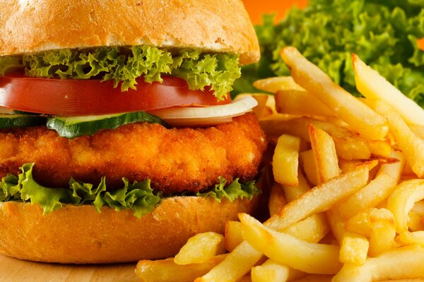 Hamburger avec côtelette épaisse, légumes verts juteux, tomates, oignons entourés de frites