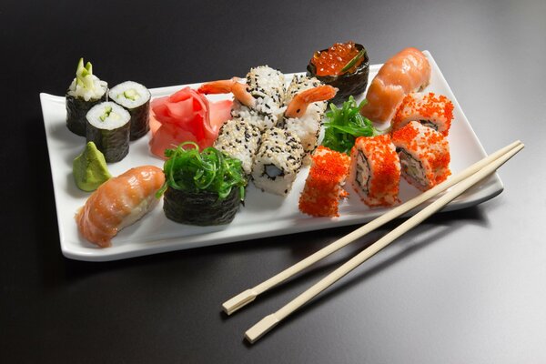 A plate with sushi and rolls, wasabi and ginger