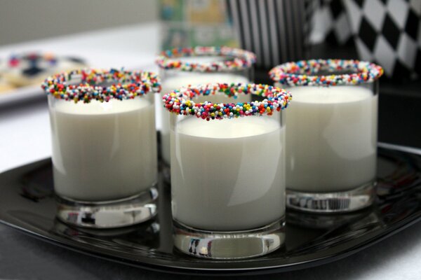 Quatre verres de lait sur une assiette noire