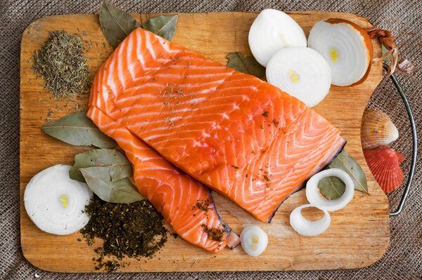 Ein Stück roter Fisch auf einer Tafel mit Gewürzen