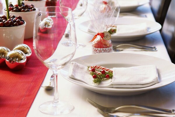 Christmas table service with golden balls, berries and sweet sticks