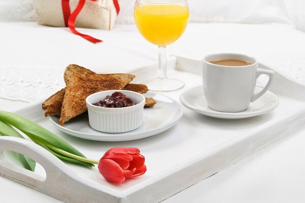 Desayuno por la mañana con tostadas y mermelada, zumo y café en la bandeja