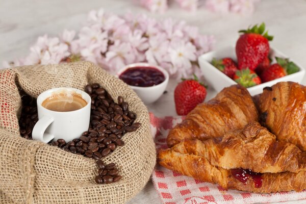 Eine Tasse Kaffee unter den Bohnen und frische Croissants dazu