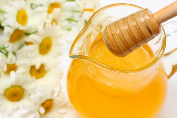 Miel avec une cuillère sur un fond de marguerites