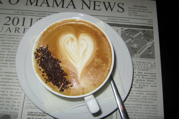 Kaffeetasse mit Schaum und Löffel auf Zeitung