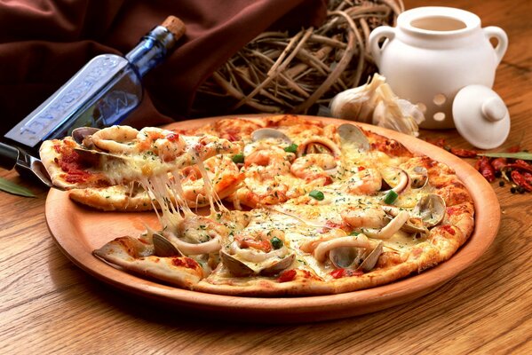 Pizza z małżami i kalmarami na tle butelki i kosza