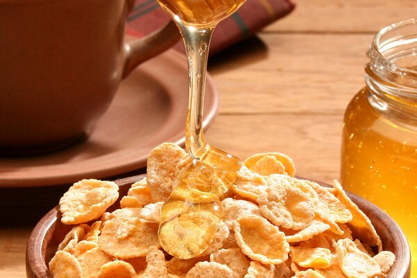Honey drips onto the cereal in the plate
