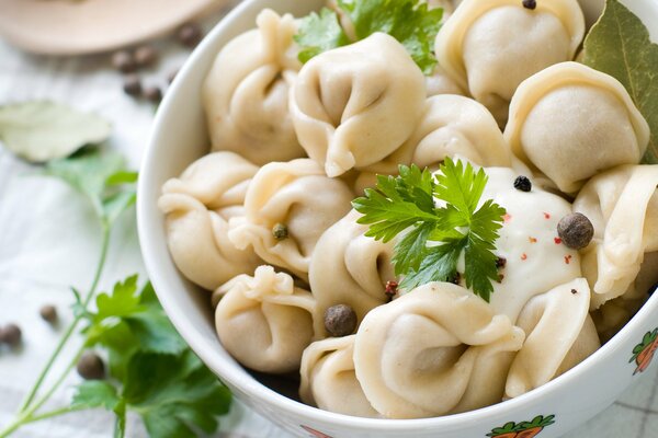 A plate of dumplings with herbs and sour cream