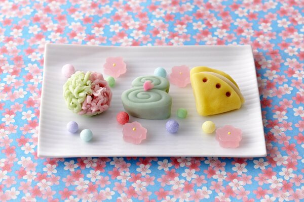 Caramelle gommose colorate su un piatto su sfondo floreale