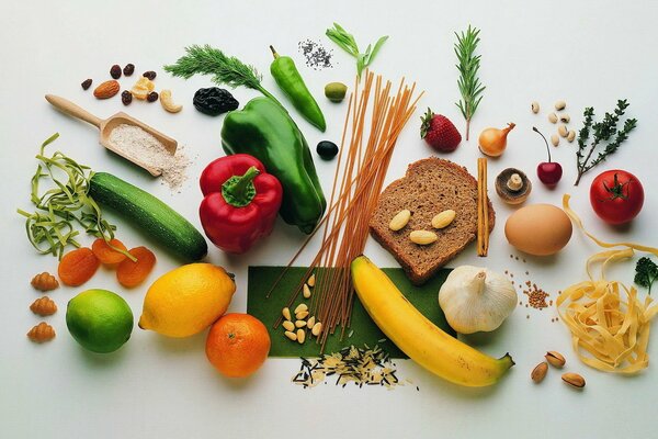 Sobre un fondo blanco se encuentran verduras, frutas pan cereales