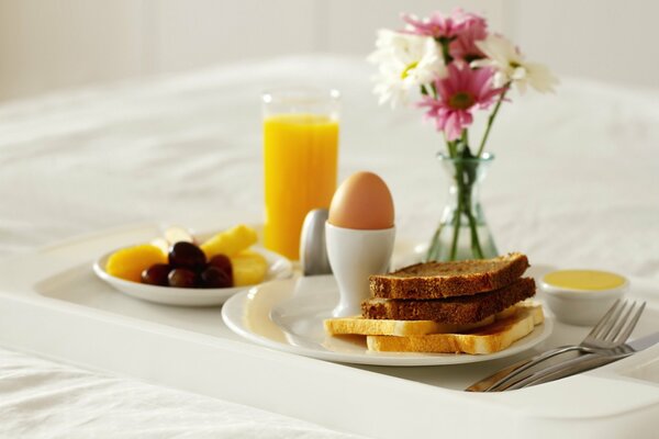 Ein Frühstück mit Ei, Toast, Oliven und Orangensaft wird serviert