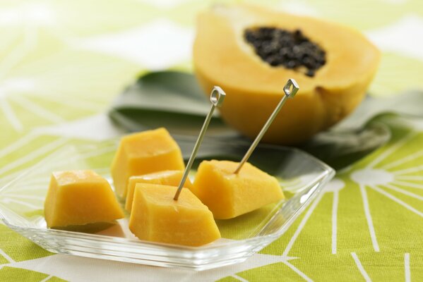 Trozos de papaya en pinchos en un plato transparente