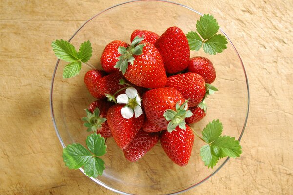Piatto di fragole succose con foglie verdi