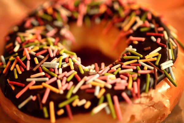 Fotografia macro. Foto di una ciambella glassata al cioccolato e cosparsa di pasticceria