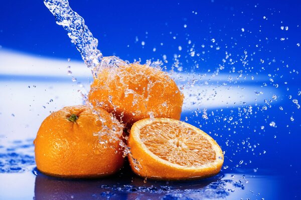 Naranjas jugosas en salpicaduras de agua en un fondo azul