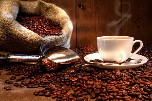 Grains de café éparpillés sur la table avec une tasse de café