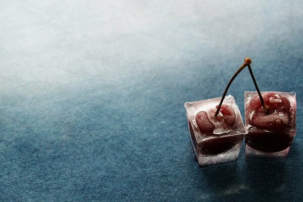 Deux baies de cerise dans des morceaux de glace