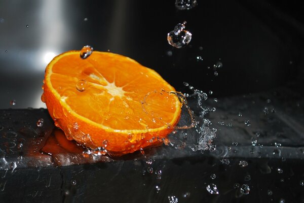 Saftige und geschnittene Orange auf dunklem Hintergrund