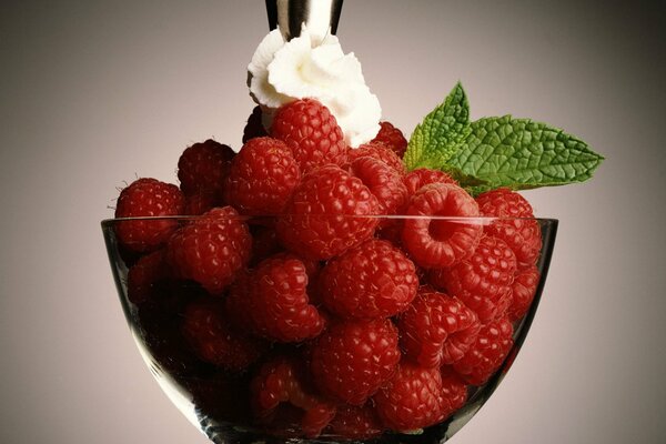 Raspberries with mint and buttercream in a transparent cream bowl