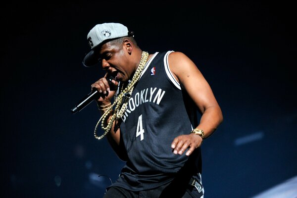 Jay-Z in maglia nera e catene con microfono P mani