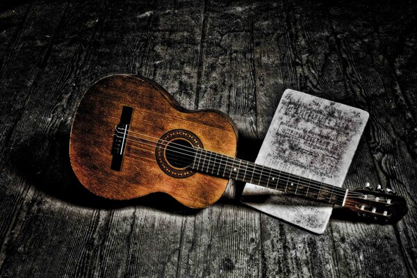 Gitarre und Noten liegen auf dem Holzboden