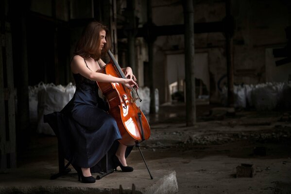 Mädchen im schwarzen Kleid sitzt mit einem Cello