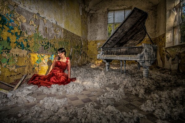 A girl in a red dress is sitting near the piano