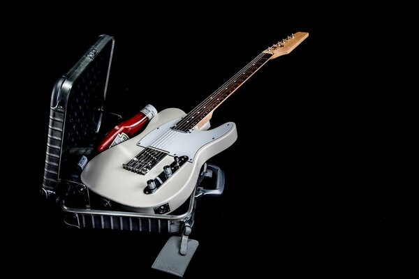 A guitar peeks out of a metal suitcase