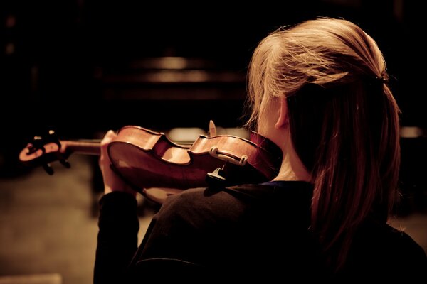 La chica toca el violín. Vista posterior