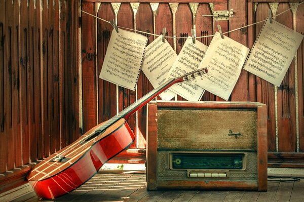 Guitar and an old radio on the background of hanging notes