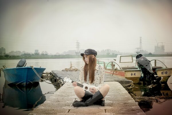 Chica con gorra sentada en el muelle